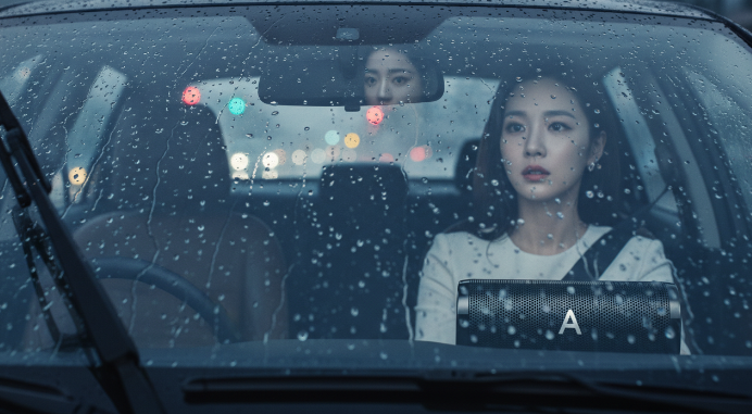 비 오는 날 자동차 윈드실드에 빗방울이 맺힌 모습과 흐릿하게 보이는 전방 시야